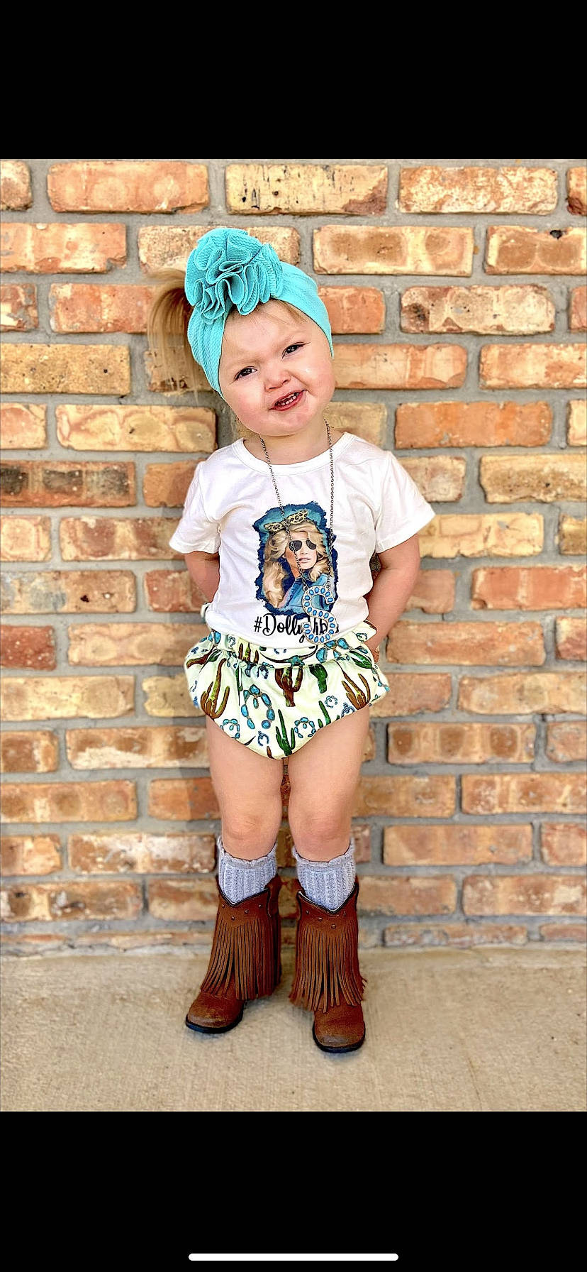 Saige is registered to the contest to win money with this photo: baby_toddler_clothing, blue, brick, brickwork, cool, happy, headgear, headwear, jewellery, knee, leg, orange, person, pink, skin, sleeve, smile, standing, t_shirt, thigh