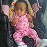 baby, infant, car_seat, pacifier, pink_clothing, barbie, sneakers, nike, footwear, child, cute, patterned, seat_belt, indoor, portrait, young_child, person, clothing, accessory, bracelet