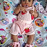 baby, infant, pacifier, pink_clothing, crocheted_shoes, strawberry_design, blanket, cartoon_characters, lying_down, cute, child, indoors, soft_fabric, colorful, closeup, portrait, face, hands, feet, sleepwear