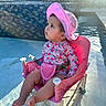 baby, child, pink_hat, floral_clothing, chair, pool, water, sunlight, outdoor, summer, skin, earring, foot, face, portrait, seat, reflection, daylight, curious, baby_girl