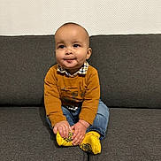 Leo participe au concours pour gagner de l'argent avec cette photo : baby, child, smiling, sitting, couch, indoor, yellow_socks, mustard_sweater, blue_jeans, hands, face, head, wall, texture, plaid_shirt, person, young_child, feet, happy, cozy