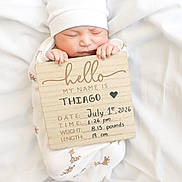 Thiago joined the competition — help win amazing prizes! newborn, baby, infant, sleeping, hat, white_clothing, giraffe_pattern, wooden_sign, text, blanket, soft, peaceful, cute, portrait, child, hands, face, bed, resting, announcement