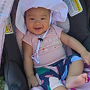 Everly is registered to the contest to win money with this photo: baby, child, smiling, hat, stroller, blanket, clothing, infant, cute, outdoor, person, face, happy, legs, feet, sunhat, patterned_pants, seat, comfort, relaxing