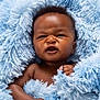 baby, blue_blanket, child, closeup, cozy, curly_hair, cute, expression, face, fuzzy, hand, indoors, infant, newborn, person, portrait, skin, small, soft, wrapped