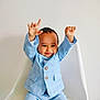 toddler, child, smiling, blue_suit, checkered_suit, raised_hands, white_chair, indoor, portrait, happy, cute, fashion, casual, person, young_child, baby_face, seated, celebration, joy, minimalist_background
