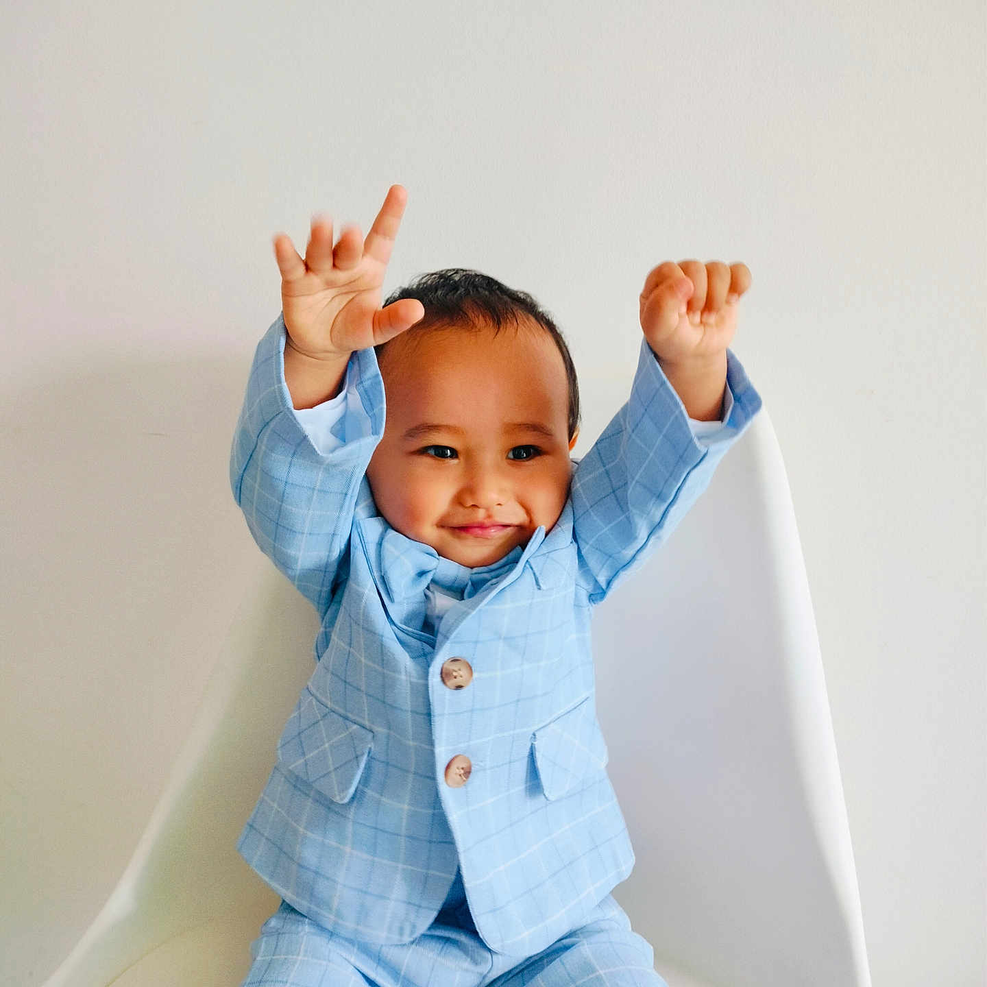 Devick joined the competition — help win amazing prizes! baby_face, blue_suit, casual, celebration, checkered_suit, child, cute, fashion, happy, indoor, joy, minimalist_background, person, portrait, raised_hands, seated, smiling, toddler, white_chair, young_child