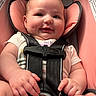 baby, car_seat, straps, smile, infant, child, pink, clothing, cute, happy, seat, safety, hands, legs, head, face, indoors, person, young, portrait