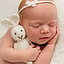 Amara is registered to the contest to win money with this photo: baby, newborn, sleeping, knitted_toy, bunny, headband, white, blanket, soft, cute, peaceful, infant, child, portrait, cuddling, resting, closeup, hand, skin, innocence