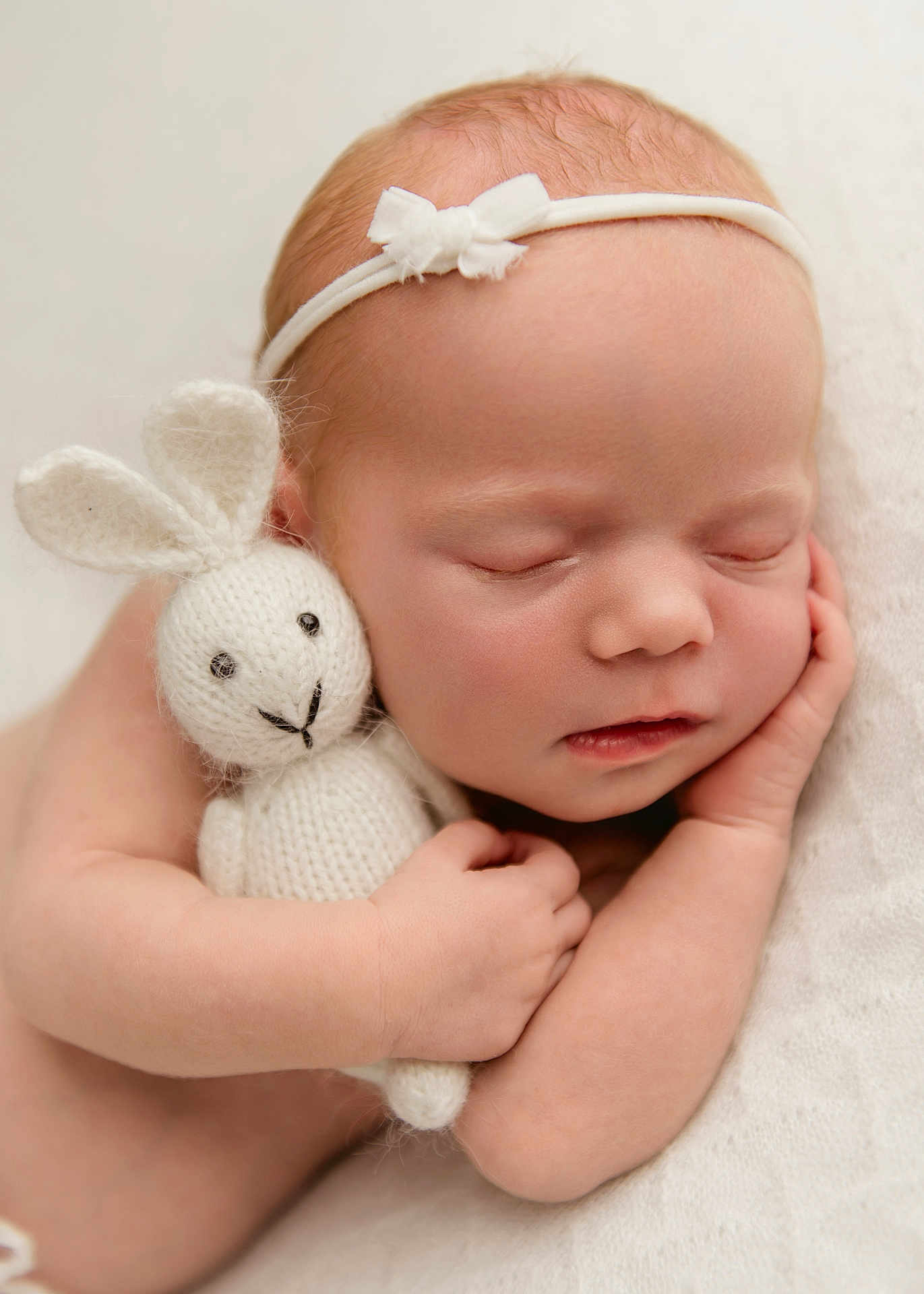 Amara is registered to the contest to win money with this photo: baby, newborn, sleeping, knitted_toy, bunny, headband, white, blanket, soft, cute, peaceful, infant, child, portrait, cuddling, resting, closeup, hand, skin, innocence