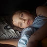 Sebastian is registered to the contest to win money with this photo: child, bed, blanket, face, portrait, sleep, resting, indoor, calm, young, pillow, blue, polka_dot, expression, person, closeup, soft_light, relaxation, comfort, night