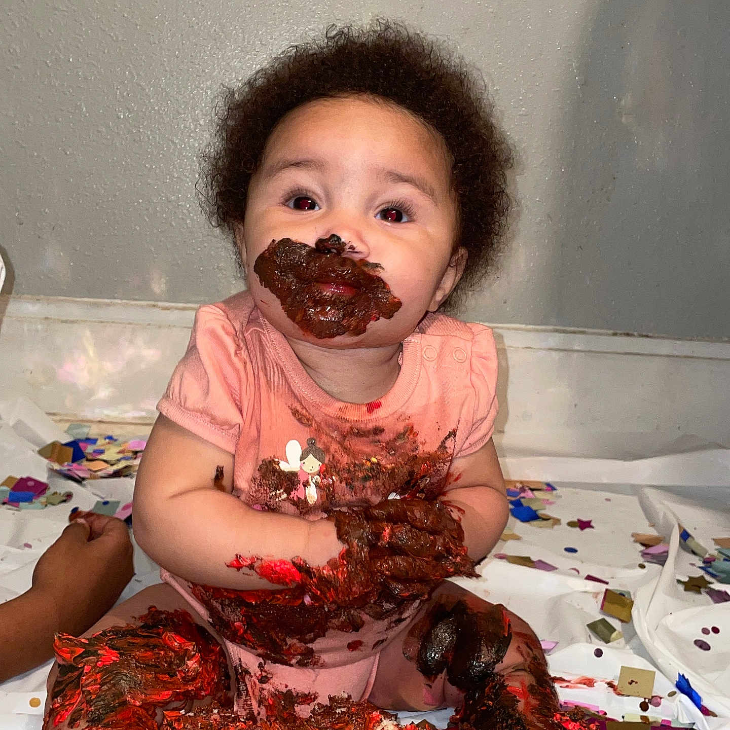 Kihanna is registered to the contest to win money with this photo: baby, cake, celebration, child, chocolate, confetti, face, floor, food, fun, hands, happy, indoor, legs, messy, party, pink_clothing, sitting, smile, wall