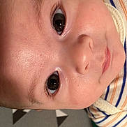 Liam is registered to the contest to win money with this photo: baby, face, eyes, skin, closeup, infant, portrait, striped_clothing, curious, young_child, head, human, child, cute, expression, indoors, soft_light, newborn, attention, calm