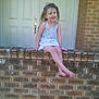 Kailynn is registered to the contest to win money with this photo: child, girl, smiling, barefoot, brick_wall, dress, outdoor, door, happy, young, hair, sitting, front_yard, home, casual, sunlight, daytime, portrait, person, suburban