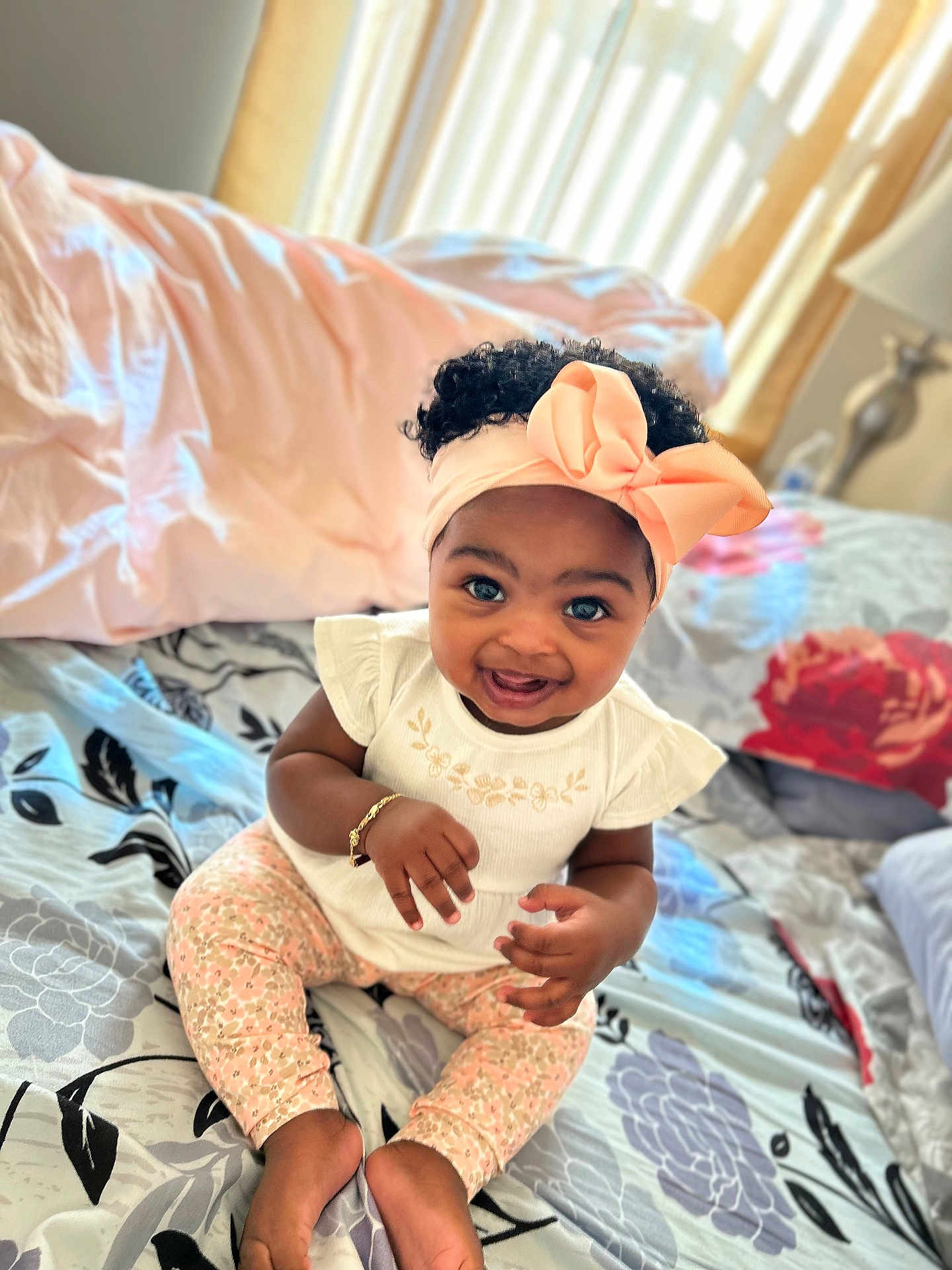 Maddison joined the competition — help win amazing prizes! baby, child, smiling, headband, bow, sitting, bed, blanket, pillow, curtains, bracelet, clothing, floral_pattern, indoors, happy, person, portrait, cute, toddler, room