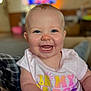 baby, smiling, blue_eyes, indoor, shirt, colorful_text, happy, child, portrait, cute, infant, skin, face, sitting, person, human, young, cheerful, closeup, warm_lighting