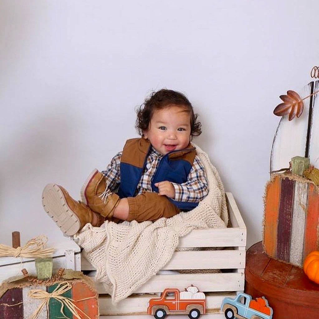 Anthony is registered to the contest to win money with this photo: baby, baby_toddler_clothing, calabaza, child, comfort, couch, cucurbita, dress, event, gourd, happy, living_room, person, pumpkin, sitting, smile, tire, toddler, vehicle, wheel