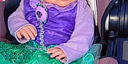 Valentina is registered to the contest to win money with this photo: baby, car_seat, child, clothing, costume, cute, fabric, face, floral_pattern, green_skirt, hands, indoor, infant, looking_away, person, portrait, purple_clothing, seatbelt, soft_lighting, sparkle