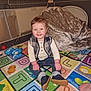 toddler, child, smiling, indoor, playmat, alphabet, colorful, clothing, vest, jeans, shoes, blanket, plush, playpen, happy, sitting, toy, floor, person, home