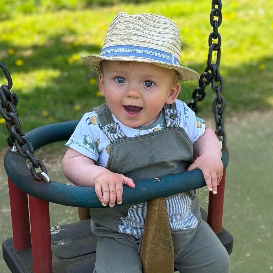 Vinnie joined the competition — help win amazing prizes! baby, clothing, face, grass, hat, head, nature, outdoorplayarea, outdoors, pants, park, person, photography, plant, playarea, portrait, sitting, swing, toy, vegetation