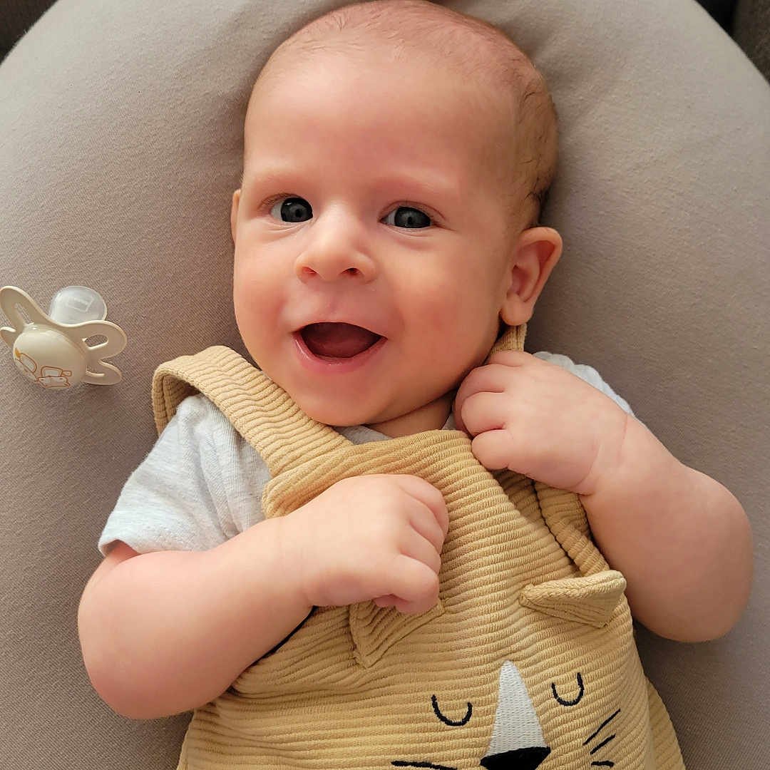 Estéban a rejoint le concours — aidez-le/la à gagner de superbes lots ! baby, beige_clothing, cat_design, child, closeup, comfortable, cushion, cute, eyes, hands, happy, indoor, infant, light_skin, pacifier, portrait, relaxed, short_hair, smiling, soft_fabric