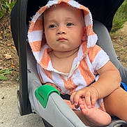 Aslan participe au concours pour gagner de l'argent avec cette photo : baby, child, car_seat, hooded_towel, orange_stripes, outdoor, sidewalk, greenery, hand, foot, curious, toddler, person, infant, seat, cute, casual, daylight, portrait, expression