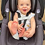 baby, car_seat, smiling, child, outdoor, happy, infant, seatbelt, foot, hand, person, clothing, head, face, safety, playful, cute, skin, fabric, seat
