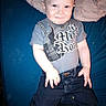 Justin is registered to the contest to win money with this photo: baby, child, infant, portrait, sitting, smiling, face, eyes, clothing, shirt, guitar, jeans, denim, couch, blanket, indoor, blue_background, casual, happy, photograph