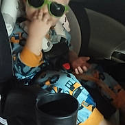 Justin is registered to the contest to win money with this photo: child, toddler, car_seat, car, sunglasses, green_sunglasses, pajamas, seated, portrait, indoor, vehicle, backseat, safety_harness, blond_hair, hand_gesture, fashion, playful, casual, photograph, travel