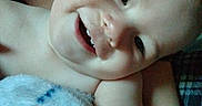 Apollo is registered to the contest to win money with this photo: adult_hand, baby, blanket, blue_blanket, child, close_up, cozy, cuddling, eyes, face, fuzzy_blanket, grinning, home, indoor, infant, lying_down, portrait, smiling, teeth, upside_down