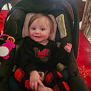 Emily is registered to the contest to win money with this photo: baby, big_eyes, black_top, car_seat, child, face, floral_curtains, hand, heart_sequin, infant, pink_mirror, plaid_leggings, red_black_pattern, seat_buckle, smiling, sock, stroller_handle, tablecloth, toy, wooden_chair