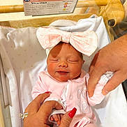 Gigi is registered to the contest to win money with this photo: baby, bassinet, blanket, bow, closeup, crib, face, gentle_touch, girl, hands, hospital, hospital_card, infant, nails, newborn, person, pink_outfit, ring, skin, sleeping