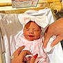 baby, bassinet, blanket, bow, closeup, crib, face, gentle_touch, girl, hands, hospital, hospital_card, infant, nails, newborn, person, pink_outfit, ring, skin, sleeping