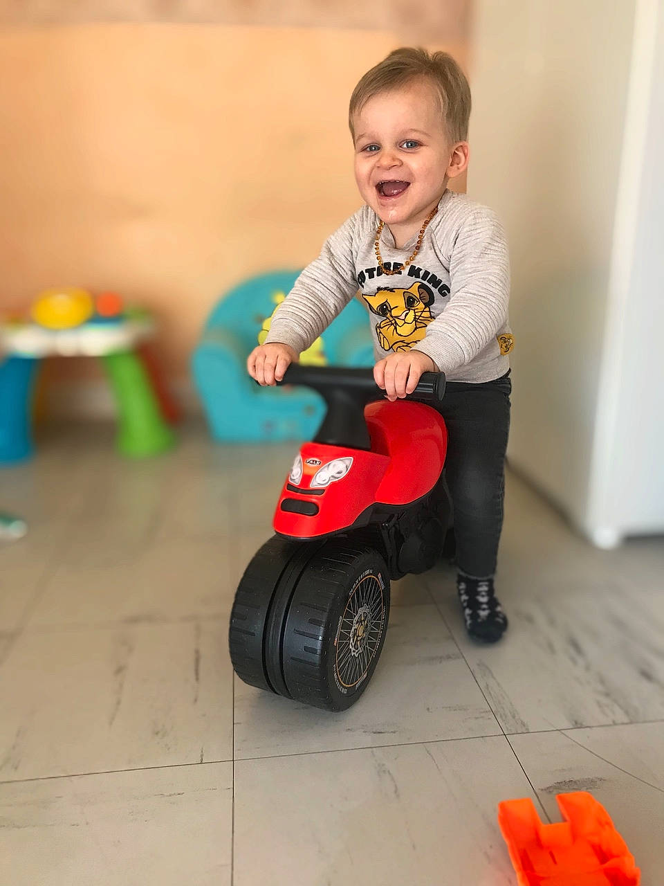 Kenzo participe au concours pour gagner de l'argent avec cette photo : automotive_tire, baby_playing_with_toys, baby_toddler_clothing, child, floor, flooring, fun, happy, joy, leg, orange, person, red, riding_toy, rolling, shoe, smile, tire, toddler, toy