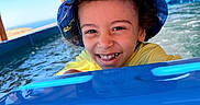 Adam is registered to the contest to win money with this photo: blue, bucket_hat, child, curly_hair, happy, laughing, ocean, outdoors, playful, pool, portrait, seaside, smiling, splashing, summer, swimming, vacation, water, water_slide, yellow_shirt
