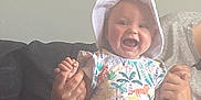 Kyra is registered to the contest to win money with this photo: baby, babylaughing, bonnet, cap, clothing, couch, dress, face, furniture, happy, hat, head, laughing, newborn, person, photography, portrait, quilt, sitting, t_shirt