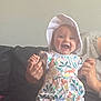 baby, babylaughing, bonnet, cap, clothing, couch, dress, face, furniture, happy, hat, head, laughing, newborn, person, photography, portrait, quilt, sitting, t_shirt