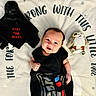 baby, black_clothing, blanket, child, cozy, cute, darth_vader, face, happy, indoor, infant, lying_down, playful, plush_toy, portrait, smiling, soft_texture, star_wars, stuffed_animal, toy