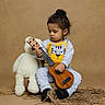Dominick joined the competition — help win amazing prizes! black_socks, brown_background, child, cute, focused, gray_clothing, hair_bun, indoors, musical_instrument, musician, portrait, rope, sitting, studio, teddy_bear, tiger_shirt, toddler, toy, ukulele, warm_lighting