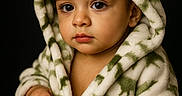 Dominick joined the competition — help win amazing prizes! baby, black_background, blanket, bracelet, child, clothing, eyes, face, green, hands, hood, indoor, photography, plush, portrait, robe, serious, sitting, studio, white