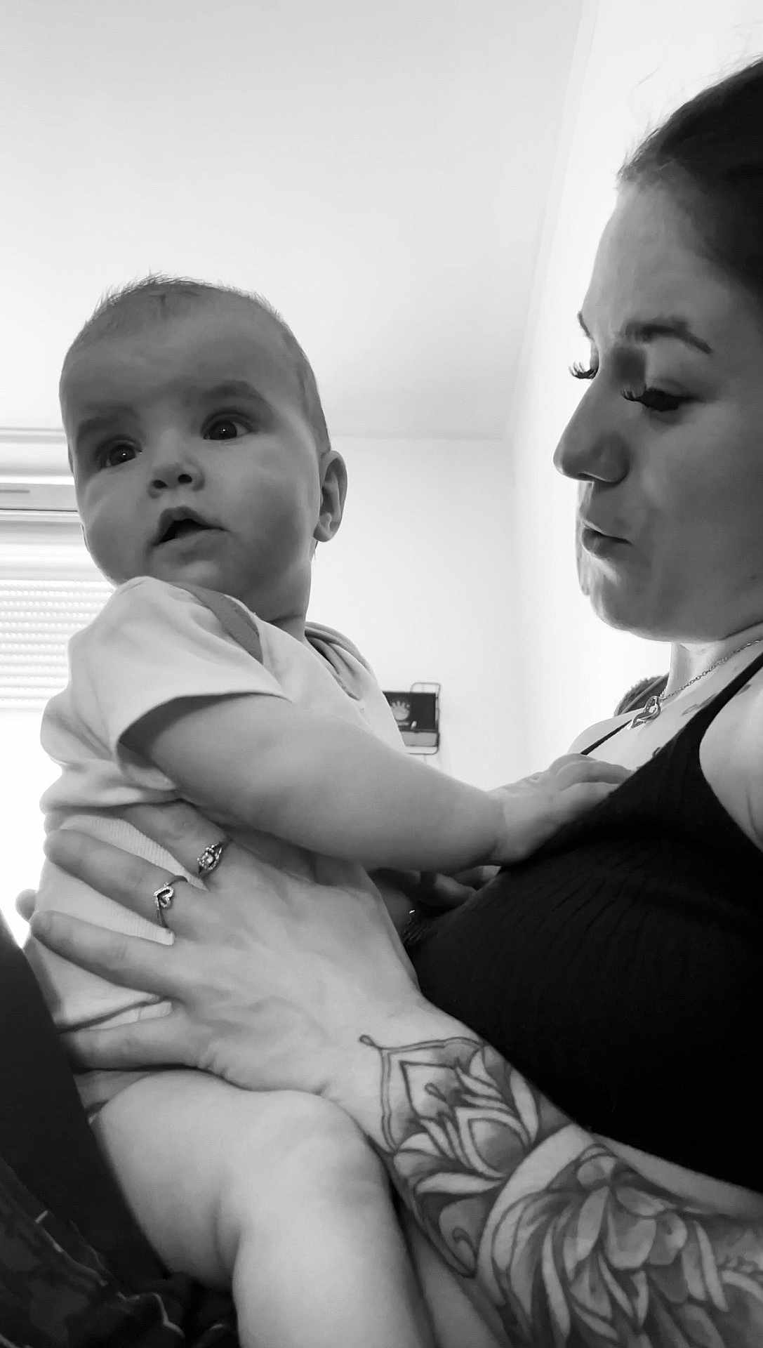 Adryanna participe au concours pour gagner de l'argent avec cette photo : baby, adult, black_and_white, tattoo, holding, indoor, person, child, face, portrait, curious, expression, hand, arm, clothing, window, light, skin, closeup, love