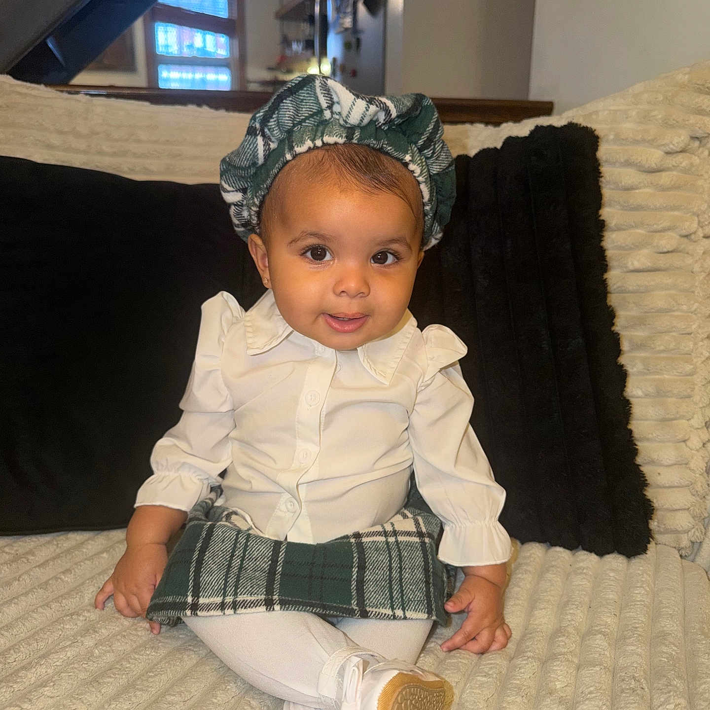 Jisselly is registered to the contest to win money with this photo: baby, child, clothing, couch, cozy, cute, fashion, footwear, green_skirt, happy, headwear, home, indoor, person, plaid, portrait, sitting, smile, white_shirt, young_child