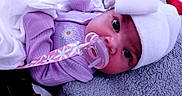 Emarelys joined the competition — help win amazing prizes! adorable, baby, blanket, child, closeup, comfort, cute, daisy_embroidery, eyes, face, hat, headwear, indoors, infant, lying_down, pacifier, purple_clothing, resting, soft_texture, white_hat