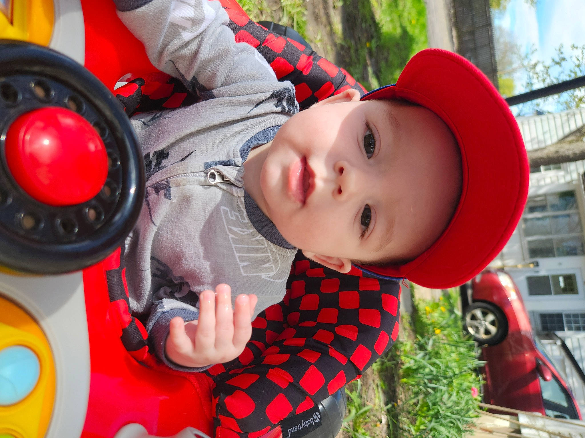 Jaxon is registered to the contest to win money with this photo: baby, child, fun, grass, happy, hat, headgear, headwear, leisure, people, person, personal_protective_equipment, plant, recreation, smile, sun_hat, tire, toddler, tree, vehicle