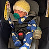 baby, infant, car_seat, pacifier, knitted_hat, onesie, sleeping, child, bottle, straps, safety, indoor, blue_clothing, yellow_hat, face, newborn, cute, resting, seat, baby_gear