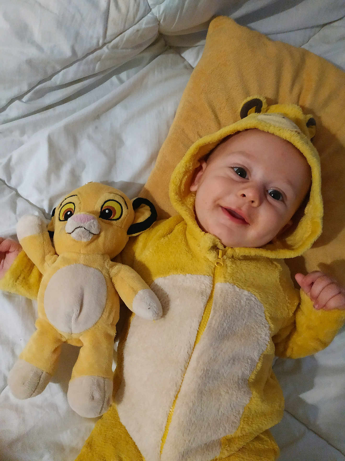 Mahé a rejoint le concours — aidez-le/la à gagner de superbes lots ! baby, child, plush_toy, yellow_onesie, bed, pillow, smile, happy, cute, infant, soft_toy, costume, hood, lying_down, indoor, person, toddler, animal_onesie, childrens_clothing, stuffed_animal