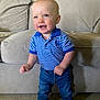 toddler, child, smiling, standing, indoor, couch, clothing, jeans, polo_shirt, blue, striped, carpet, footwear, happy, person, young_child, cute, face, short_hair, home