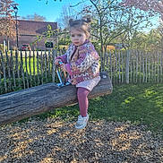 Lilha participe au concours pour gagner de l'argent avec cette photo : child, daytime, expression, face, fence, grass, jacket, nature, outdoor, park, person, pink_tights, play, playground, sneakers, spring, sunlight, toddler, tree, wooden_seesaw