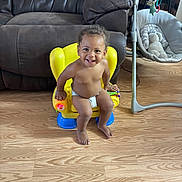 Jovanni joined the competition — help win amazing prizes! baby, child, toddler, smiling, happy, sitting, portrait, indoor, living_room, yellow_chair, baby_chair, diaper, toy, play_gym, baby_rocker, couch, wooden_floor, furniture, barefoot, home