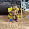 baby, child, toddler, smiling, happy, sitting, portrait, indoor, living_room, yellow_chair, baby_chair, diaper, toy, play_gym, baby_rocker, couch, wooden_floor, furniture, barefoot, home