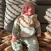 Marco participe au concours pour gagner de l'argent avec cette photo : baby, smiling, sitting, hoodie, pants, socks, blanket, sunlight, shadow, striped_shadow, indoor, cozy, happy, child, infant, face, head, clothing, warm, couch